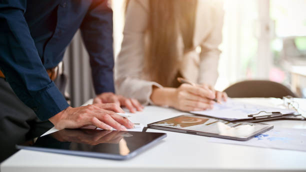 Two professional businesspeople for financial analysts are working on financial report and analyzing financial data together in the office. cropped image